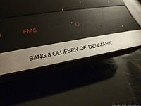 Close-up of the Bang & Olufsen brand label and part of the analog tuner scale.
