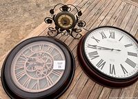 Photo showing three clocks: two large wall clocks and one smaller vintage standing clock.