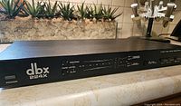 Front angled view of the black DBX 224X rack-mountable audio noise reduction system showing power switch, tape level meter, logo, and control buttons.