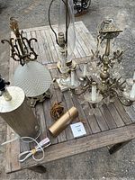 All six lights arranged on outdoor wooden table including chandelier, four table lamps, and art display lamp.