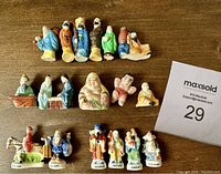 Overview of all 17 ceramic or porcelain Asian miniature figurines arranged on a wooden surface.