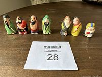 Wide shot of all seven Asian miniature hand painted figurines lined up.
