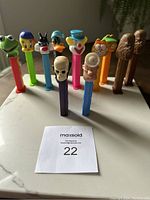 Lot of 11 PEZ dispensers arranged standing in a row showing character heads and stems.