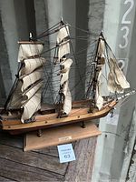Overall view of the detailed Cutty Sark Clipper Ship wooden model with fabric sails and rigging mounted on a wooden stand.
