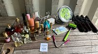 Wide angle photo of all items showing perfume bottles, mirror, massager, threader, needles, and hangers on wood surface