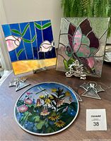 Two stained glass panels and three suncatchers shown on table: butterfly panel with butterfly and wire antennae, fish panel with blue, green, pink, and yellow colors, two beveled glass angel suncatchers, round floral plastic suncatcher.