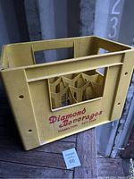 Photo showing the full yellow plastic crate with Diamond Beverages logo and Hamilton phone number, some dust visible.
