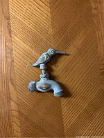 Angle showing top and side of bird hose spout on wood surface.