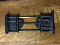 Top view of the bookshelf end cap showing decorative metal sides with embossed lion and three brass rods connecting each side horizontally.