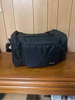 View of the closed black camera case showcasing front pocket and brand label 'Pentax'