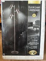 Photo of the floor lamp in original packaging showing three adjustable metal shade bulbs and matte black finish.