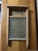 Front view of vintage wooden washboard showing clear textured glass scrubbing surface inside wooden frame branded 'PEARL Canadian Woodenware Typhoon'.