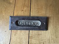 Front view of metal letter slot with word 'LETTERS' embossed on surface.
