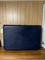 Closed massage table showing blue vinyl exterior surface, slight wear visible.