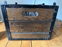 Front view of wooden milk crate showing brand and location details