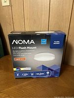 Photo of the NOMA LED Flush Mount Light in its box showing front of packaging with product details.