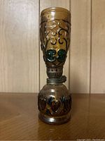 Front view of vintage oil lantern showing painted glass with green and blue clover designs and heart patterns on metal base.