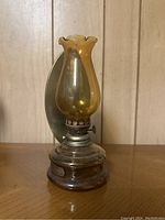 Front view of the vintage oil lantern showing the yellow glass chimney and metal reflector backing.