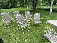 Five outdoor mesh chairs arranged on a lawn with beige metal frames and decorative backs.