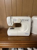 Front view of white Omega sewing machine showing stitch pattern options and machine body.