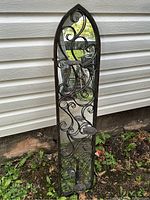 Front view showing stylized metal scrollwork and three fold-away candle holders on narrow tall mirror.