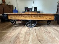 Side view showing wood plank side with stenciled “P.E. Hanna Foundry” marking and cast iron wheels.