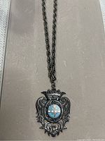 Full view of pendant necklace with chain on neutral background