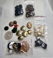 Top view of assorted vintage buttons spread out and grouped, with some in small plastic bags showing variety in style and material.