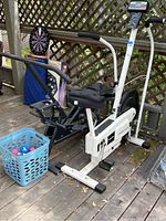 Panasonic Prairub exercise bike and Health Rider rowing machine side by side on wooden deck with basket of hand weights