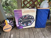 Overall view of poker set box, smash ball paddles, electronic dartboard, and badminton blue case