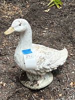 Full side view of the painted cement goose garden statue set outdoors on mulch.