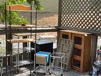 Photo showing two wooden cabinets with wire screen drop-down doors, wicker and metal shelving unit, chrome roll-around racks, and IKEA cabinet.