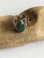 Front view of silver ring showing greenish blue stone and unusual band design.