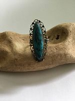 Front view of vintage American Indian turquoise silver ring with elongated marquise turquoise and scalloped silver bezel on wood background.