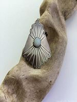 Front view of pendant showing detailed hand-engraved silver pattern and central opal cabochon.