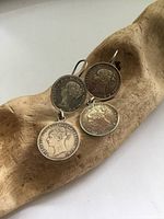 Front view of antique silver coin earrings displaying the obverse sides of the coins with profiles and inscriptions.