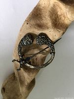 Front view of antique sterling silver thistle kilt clip brooch showing circular design and thistle ends.