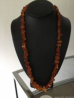 Full view of the long Baltic amber graduated necklace displayed on a black bust, showing the color and bead sizes along the length.