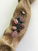 Front view of a large chunky sterling silver pendant set with polished agate, rose quartz, and garnet stones on a wooden background.