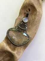 Front view of pendant displayed on wooden prop showcasing the three stones and oxidized silver setting.