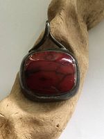Front view of a large rectangular red stone set in sterling silver with an abstract bail.