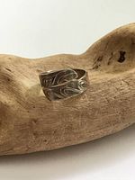 Front view of the sterling silver torque ring showing carved Indigenous design and wrap-around style.