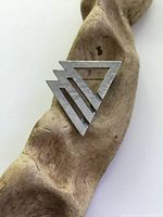 Front view of a signed pewter abstract geometric brooch, highlighting the intersecting triangular shapes and matte metal finish.