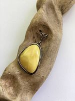 Front view of the pendant showing the polished butterscotch amber set in sterling silver with Celtic style bail.