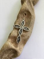 Front view of the sterling silver cross pendant displayed on a textured wooden surface to highlight design details.