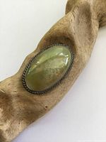 Top view of oval green agate cabochon brooch set in a sterling silver twisted rope frame.