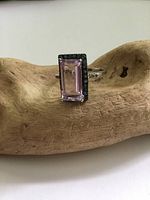Front angled view of rectangular purple amethyst glass center stone framed by blue glass on sterling silver ring, displayed on wood surface.