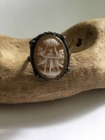 Front view of the antique sterling silver cameo ring with detailed carving of three dancers in white on a brown background.