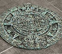Full view of round green wall plaque showing entire Mayan calendar design with textured surface.