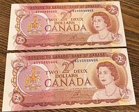 Front side of two consecutive 1974 Canadian $2 bills showing Queen Elizabeth II, serial numbers, and bank marks.